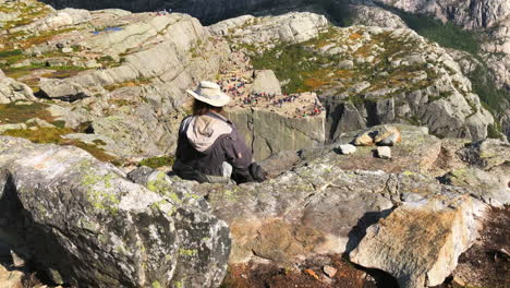 Hipster-cowboy-traveller-resting-on-the-rocky-edge-of-Preikestolen-Pulpit-Rock-in-Norway