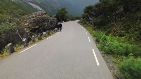 Curvy-road-in-the-area-of-Trollstigen-with-people-walking-close-to-the-cars-in-slow-mo