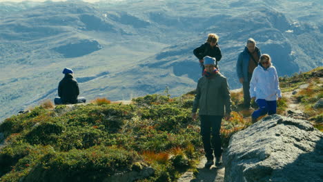 Tourists-walking-back-from-the-green-mountain-edge-of-Preikestolen-Pulpit-Rock-in-Norway