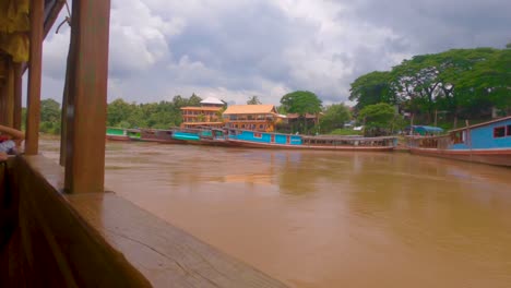 Panning-shot-of-tourists-riding-a-slow-boat-along-the-Mekong-river,-near-the-Thailand-and-Laos-border