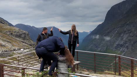 Grupo-De-Turistas-Haciendo-Movimientos-Acrobáticos-Para-Tomar-Una-Fotografía-En-El-Mirador-De-Trollstigen-En-Cámara-Lenta