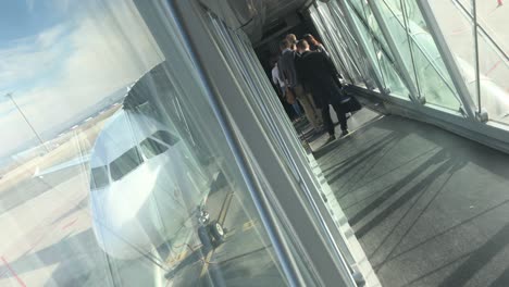 Dutch-angle-shot-of-a-jetbridge-awith-people-waiting-to-get-on-board-and-the-nose-of-a-plane