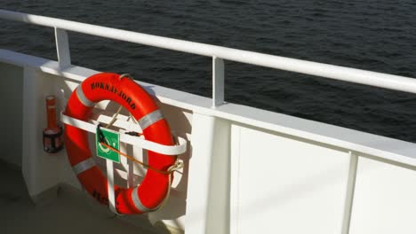 An-Der-Weißen-Stahlreling-Eines-Schiffes-Hängt-Ein-Orangefarbener-Rettungsring