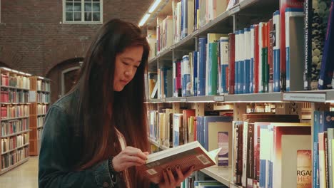 Mid-view-of-attractive-young-Asian-woman-holding-an-open-paperback-book