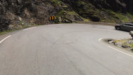 Dashcam-of-a-bus-driving-down-a-narrow-mountain-road-and-approaching-a-hairpin-turn,-Tolls-ladder-or-Trollstigen-Norway-is-a-popular-destination,-yet-several-busses-get-stuck-in-the-tight-turns
