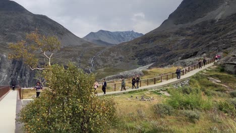 Panoramic-view-from-the-side-of-the-path-created-over-the-mountains-of-Trollstigen-with-people-walking-in-slow-motion