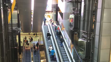 Modern-hallway-with-people-riding-escalators-and-elevators-while-rushing-to-the-gates-at-Madrid-Barajas-International-Airport-in-Spain,-modern-architecture,-construction-and-travelling-concept