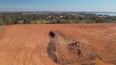 Yarrawonga,-Victoria,-Australia---18-April-2023:-Pull-back-showing-tracked-excavator-working-in-golf-course-with-lake-and-Yarrawonga-township-in-the-background