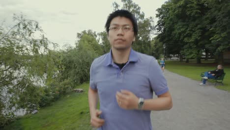 Chinese-student-exercising-on-a-running-path-near-a-scenic-waterway-with-other-joggers-in-the-background