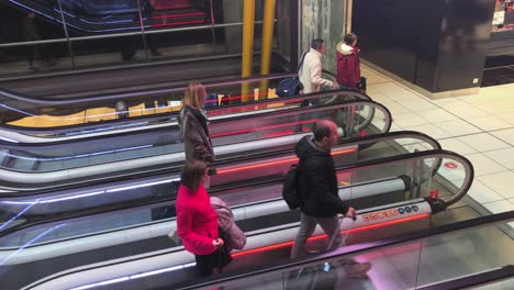 Two-row-escalator-stair-with-people,-parallel-escalator-staircase,-towing-carry-on-luggage,-busy-airport-terminal-scene,-passengers-rushing,-travel,-business-and-transportation-concept