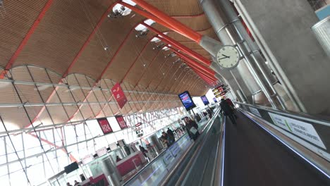 People-riding-an-express-walkway-in-both-directions-in-modern-terminal-area-of-Madrid-Barajas-International-Airport,-a-group-of-passengers-passing-by-and-walking-on-flat-escalator