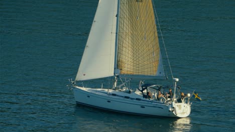 Cineflex-Gyrostabilisiertes-Hochkippen,-Luftaufnahme,-Einer-Gruppe-Von-Menschen,-Die-Auf-Einem-Segelboot-Sitzen-Und-Im-Blauen-Wasser-Der-Ostsee,-In-Den-Nordischen-Seen,-An-Einem-Sonnigen-Sommertag-Segeln