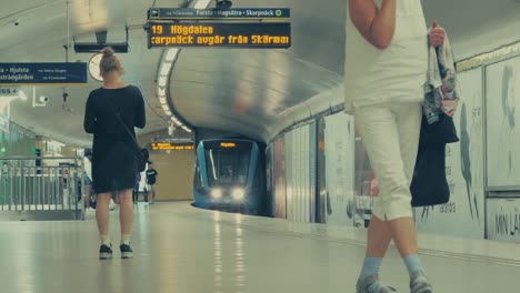 Un-Moderno-Tren-De-Metro-Que-Llega-A-La-Estación-De-Metro-De-Estocolmo,-Suecia,-Con-Gente-Esperando