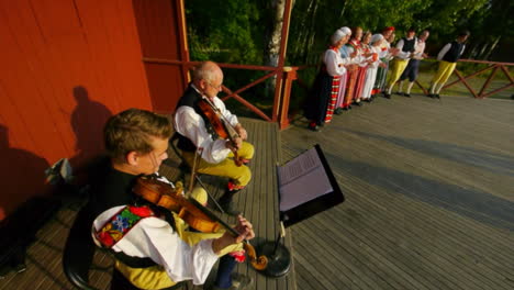 Los-Escandinavos-Felices-Y-Sonrientes-Demuestran-El-Arte-Muy-Tradicional-De-La-Danza-Folclórica-Ante-Una-Multitud-De-Espectadores-Mientras-Los-Músicos-Tocan-El-Violín.