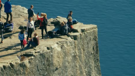 Group-of-people-posing-for-pictures-dangerously-close-to-the-cliff-above-Lysefjord,-part-of-the-Scenic-Ryfylkein-touristic-route