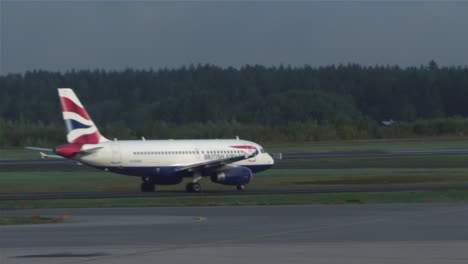 Passagierflugzeuge-Der-British-Airways-Bewegen-Sich-Auf-Der-Landebahn-Des-Flughafens-Stockholm,-Während-Ein-Tui-Airways-Flugzeug-Vorbeifliegt