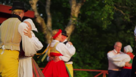 Wunderschöner-Und-Anmutiger-Schwedischer-Volkstanz,-Der-In-Der-Tradition-Der-Mittsommerfeier-Live-Auf-Der-Bühne-Präsentiert-Wird,-Während-Musiker-Geige-Spielen