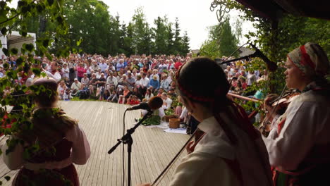 Fröhliche-Und-Lächelnde-Skandinavier-Führen-Einer-Zuschauermenge-Die-Sehr-Traditionelle-Kunst-Des-Volkstanzes-Vor,-Während-Musiker-Geige-Spielen