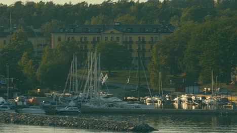 Aerial-shot-of-small-town-in-the-archipelago-near-Stockholm,-Sweden,-boats-and-sailing-boats-moored-in-harbor,-waterways-are-the-usual-way-of-transport-between-Swedens-islands,-low-to-high-angle