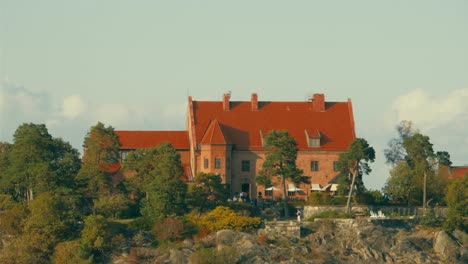 Cineflex-Gyrostabilisierte-Luftaufnahme,-Um-Ein-Rotes-Herrenhaus,-Auf-Einer-Insel,-In-Den-Nordischen-Seen,-An-Der-Ostsee,-An-Einem-Sonnigen-Sommertag,-In-Der-Nähe-Von-Stockholm,-Schweden