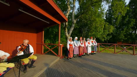 Wunderschöner-Und-Anmutiger-Schwedischer-Volkstanz,-Der-In-Der-Tradition-Der-Mittsommerfeier-Live-Auf-Der-Bühne-Präsentiert-Wird,-Während-Musiker-Geige-Spielen