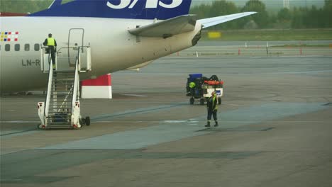 An-airplane-stair-truck-moving-away-from-an-airplane-while-another-airport-employee-walking-towards-the-plane