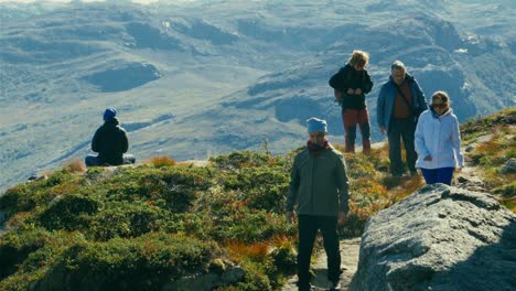 Man-in-hero-pose-on-Pulpit-rock,-zoom-pull-of-people-dangerously-close-to-the-cliff-above-Lysefjord-on-the-Scenic-Ryfylkein-touristic-route