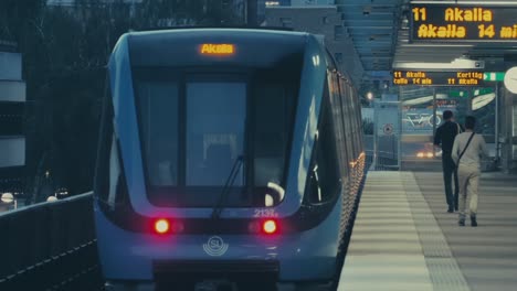 Ein-Moderner-U-Bahn-Zug-Verlässt-Die-U-Bahn-Station-Von-Stockholm,-Schweden,-Während-Menschen-Zu-Fuß-Unterwegs-Sind