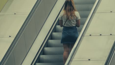A-Young-Woman-Fixing-Her-Skirt-On-Her-Way-Up-An-Escalator-In-The-Subway-Of-Stockholm