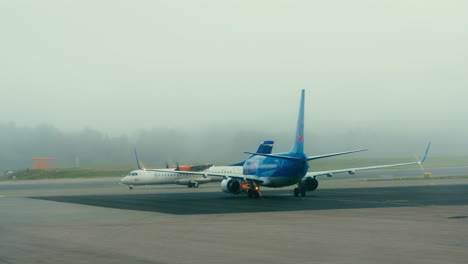Passenger-airplane-moving-on-the-runway-of-Stockholm-airport-in-Sweden-with-another-aircraft-parked