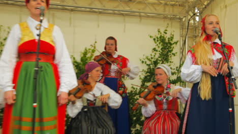 Los-Escandinavos-Felices-Y-Sonrientes-Demuestran-El-Arte-Muy-Tradicional-De-La-Danza-Folclórica-Ante-Una-Multitud-De-Espectadores-Mientras-Los-Músicos-Tocan-El-Violín.