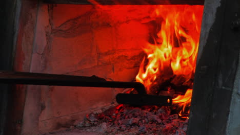Close-Up-View-Of-A-Traditional-Wood-Burning-Oven-While-The-Fire-Is-Being-Stirred-By-A-Cook