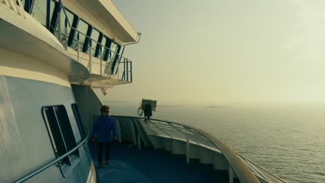 Still-shot-of-the-deck-of-a-ferry-with-a-woman-walking-in-the-wind-in-slow-motion