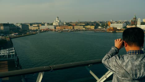 Pan-to-the-left-of-an-asian-tourist-taking-photos-of-the-city-of-Helsinki-from-a-ferry