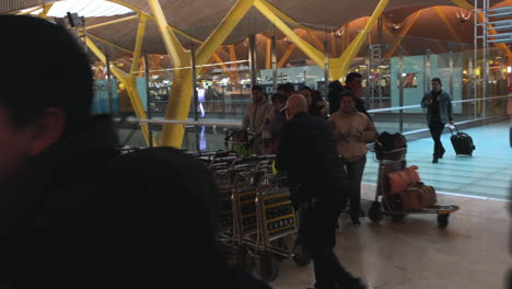 A-man-pushing-a-a-group-of-trolleys-in-a-busy-airport