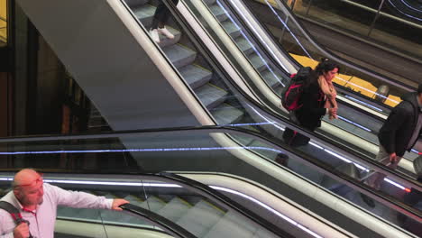Escalator-staircase-in-busy-station-terminal-area-or-airport,-people-riding-and-walking-off,-carrying-their-luggage