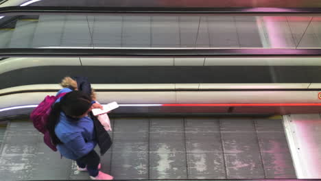 Rolltreppe-Im-Belebten-Terminalbereich-Des-Bahnhofs-Oder-Flughafens,-Menschen,-Die-Mit-Ihrem-Gepäck-Fahren-Und-Gehen