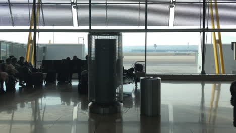 Menschen,-Die-Im-Flughafenterminal-Gehen-Und-Sitzen,-Verschiebbare-Dolly-Aufnahme-Von-Silhouetten-Von-Passagieren,-Fluggastbrücken-Und-Asphalt-Im-Hintergrund,-Reise--Und-Transportkonzept,-Flughafen-Madrid-Barajas