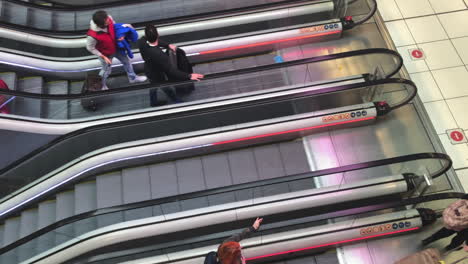 Four-rows-of-escalator-staircases-join-at-same-level,-people-stepping-of-escalator-in-modern-hallway,-airport-terminal,-modern-transportation-equipment