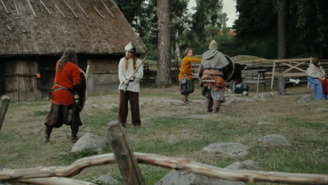 Vikingos-Socializando-Y-Practicando-Sus-Habilidades-Con-La-Espada-Entre-Sí-En-Un-Pequeño-Y-Tranquilo-Pueblo-Encantador-En-Una-Recreación-De-Un-Pueblo-De-La-época-Vikinga-En-Suecia.