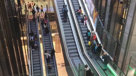 Tracking-shot-of-a-group-of-people-on-escalator-at-airport-terminal,-moving-staircase,-passengers-walking-towards-the-gates-at-airport,-travel-and-business-concept