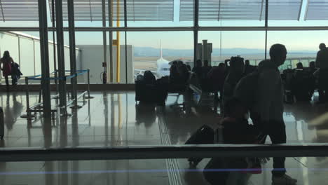 Father-with-children-walking-through-airport-terminal,-waiting-areas-and-boarding-gates-in-background,-tracking-dolly-shot,-travel,-family-and-vacation-concept