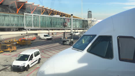 Nase-Eines-Modernen-Verkehrsflugzeugs,-Eine-Passagierbrücke-Im-Hintergrund,-Menschen,-Die-Ein-Flugzeug-Besteigen,-Servicefahrzeuge-Auf-Dem-Rollfeld,-Transport--Und-Reisekonzept,-Flughafen-Madrid-Barajas