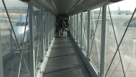 Slow-motion-shot-inside-a-jet-bridge-with-people-boarding-into-a-plane
