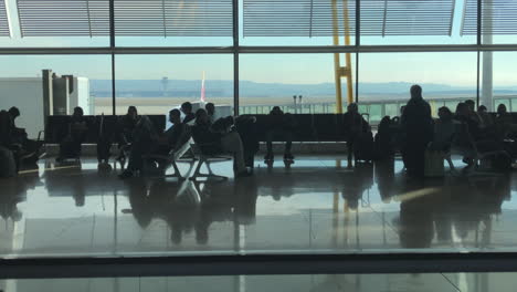 Reiseaufnahme-Rechts-Von-Menschen,-Die-Auf-Einem-Flughafen-In-Zeitlupe-Auf-Das-Boarding-Warten