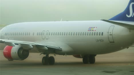 Close-up-of-an-airplane-rotating-to-the-left-and-heading-towards-the-runway-on-a-foggy-day-at-Stockholm-Arlanda
