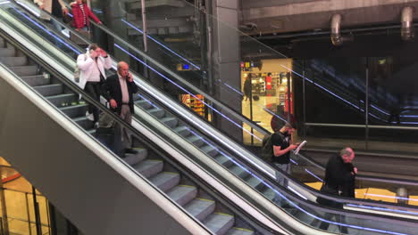 People-using-escalators-and-talking-through-a-smartphone-in-slow-motion