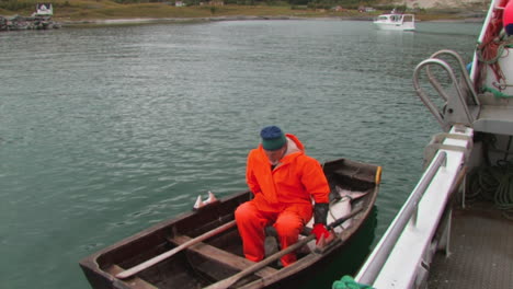 Un-Pescador-Empujando-El-Barco-Más-Grande-Y-Sentándose-En-Su-Bote-De-Remos-Más-Pequeño-En-La-Bahía