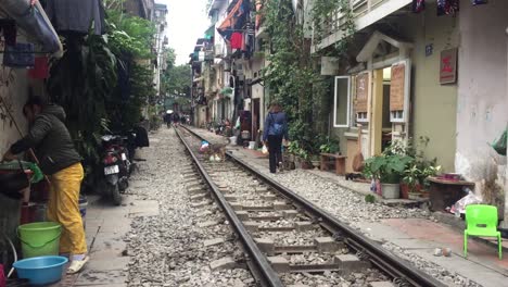 People-and-dog-on-a-quiet-railroad-track-in-Hanoi,-Vietnam