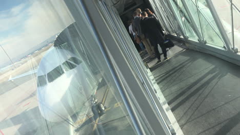 Dutch-angle-shot-of-a-jetbridge-awith-people-waiting-to-get-on-board-and-the-nose-of-a-plane